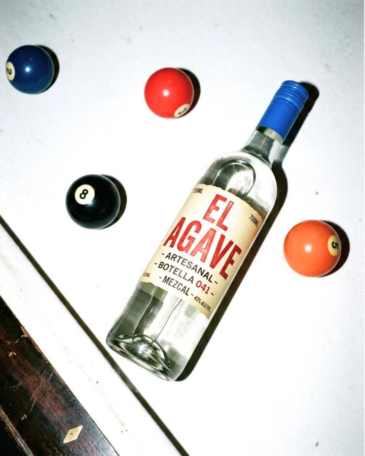 An agave spirit bottle among billiard balls